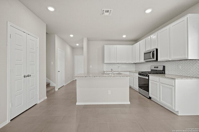 kitchen featuring light tile patterned floors, appliances with stainless steel finishes, and white cabinets