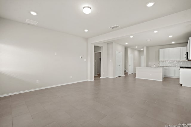 unfurnished living room with sink and tile patterned floors