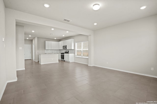 unfurnished living room featuring light tile patterned flooring and sink