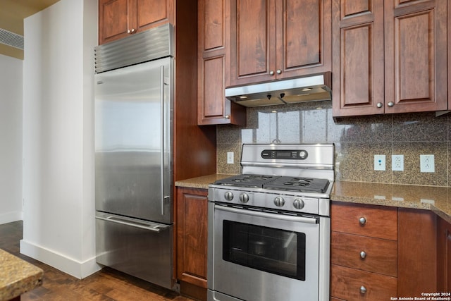 kitchen with dark wood-type flooring, light stone countertops, decorative backsplash, and stainless steel appliances