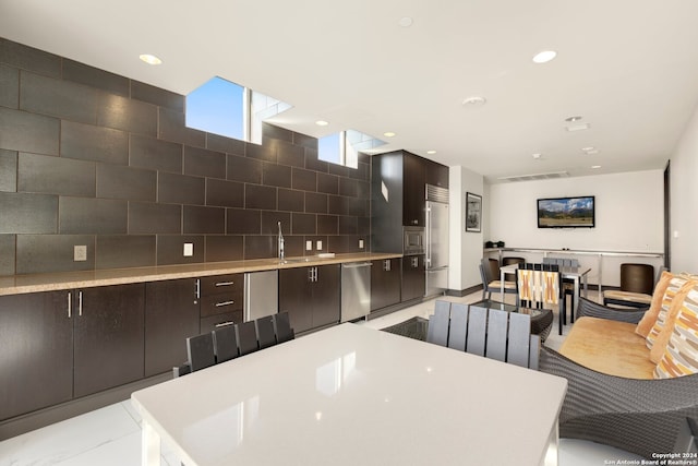 kitchen featuring tasteful backsplash, sink, a center island, stainless steel appliances, and light tile patterned floors