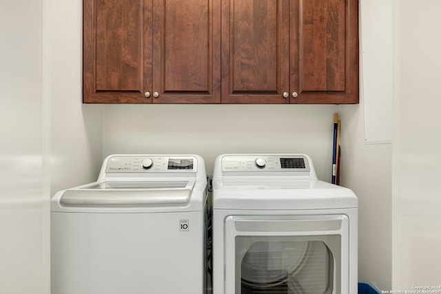 clothes washing area with cabinets and washer and clothes dryer