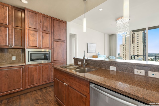 kitchen with appliances with stainless steel finishes, sink, backsplash, hanging light fixtures, and dark hardwood / wood-style floors