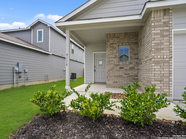 doorway to property featuring central air condition unit, a lawn, and a garage