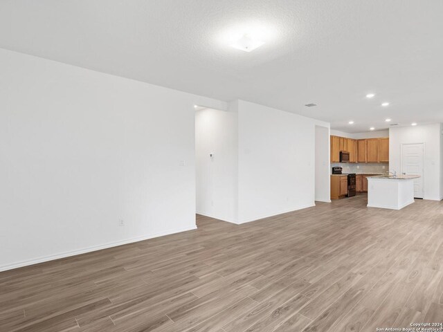 unfurnished living room with sink and light hardwood / wood-style floors