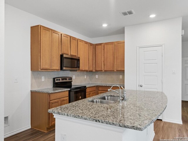 kitchen with an island with sink, tasteful backsplash, sink, and electric range oven