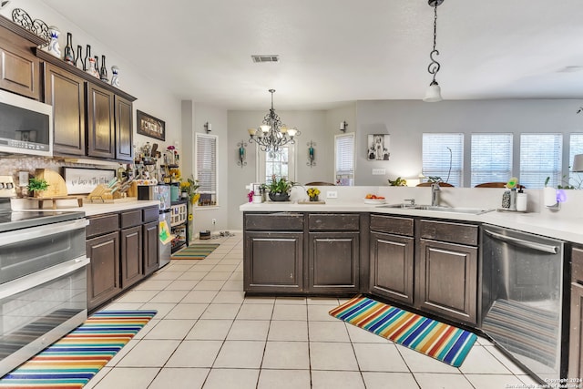 kitchen featuring dark brown cabinets, light tile patterned flooring, appliances with stainless steel finishes, and pendant lighting