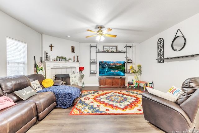 living room featuring a fireplace, ceiling fan, and light hardwood / wood-style floors