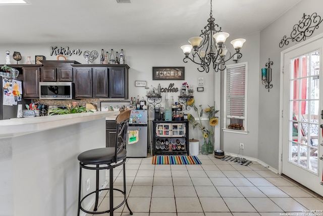 kitchen with light tile patterned floors, hanging light fixtures, fridge, dark brown cabinetry, and a chandelier