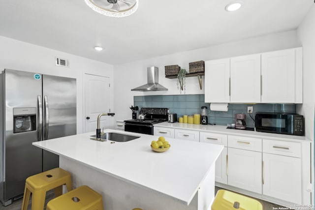 kitchen featuring a center island with sink, black appliances, sink, and wall chimney range hood