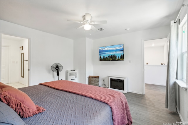 bedroom with multiple windows, wood-type flooring, ensuite bathroom, and ceiling fan