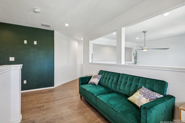 living room featuring a textured ceiling, ceiling fan, and light hardwood / wood-style floors