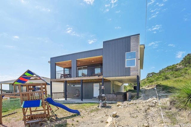 back of property featuring a balcony and a playground