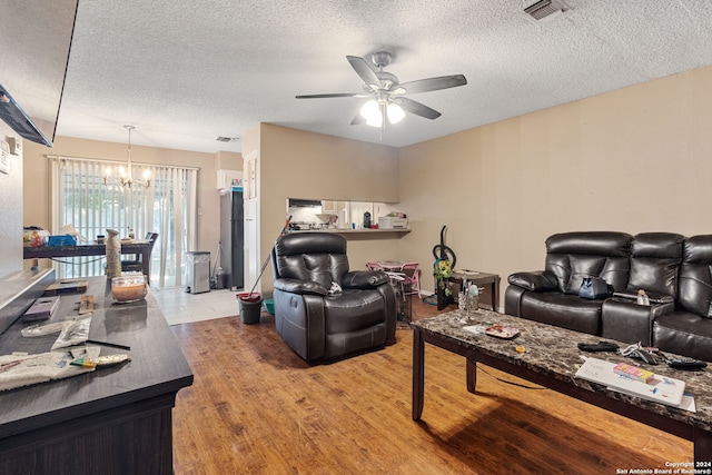 living room featuring ceiling fan with notable chandelier, a textured ceiling, and hardwood / wood-style flooring