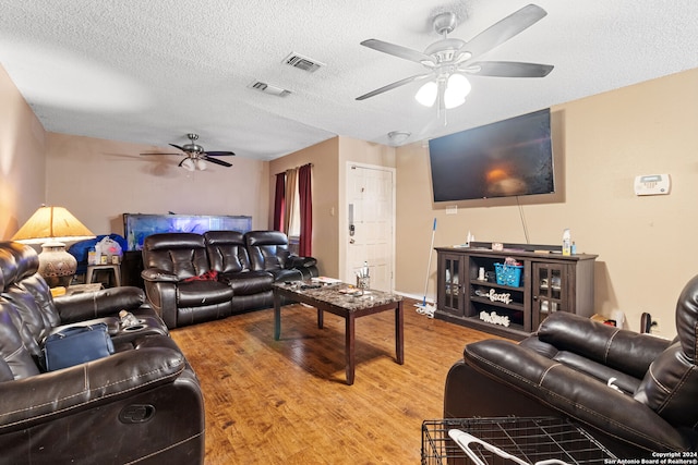 living room featuring a textured ceiling, hardwood / wood-style floors, and ceiling fan