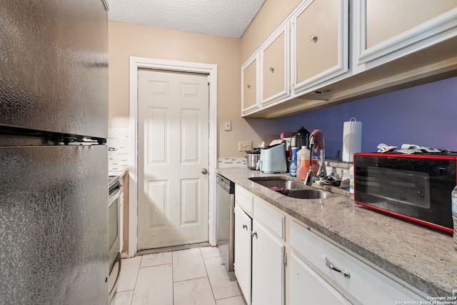 kitchen with appliances with stainless steel finishes, white cabinets, sink, and light tile patterned floors