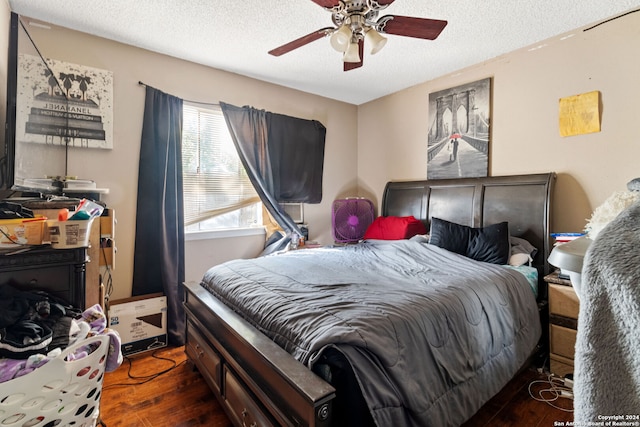 bedroom with a textured ceiling, dark wood-type flooring, and ceiling fan