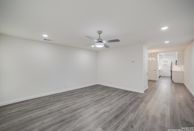 unfurnished room featuring ceiling fan with notable chandelier and hardwood / wood-style floors