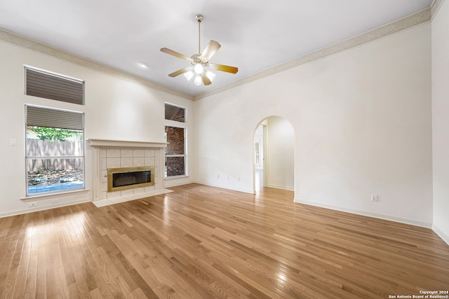 unfurnished living room with ceiling fan, a fireplace, light hardwood / wood-style flooring, and ornamental molding