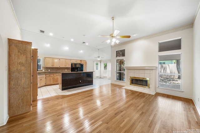 interior space with crown molding, ceiling fan, light hardwood / wood-style floors, a tiled fireplace, and black fridge