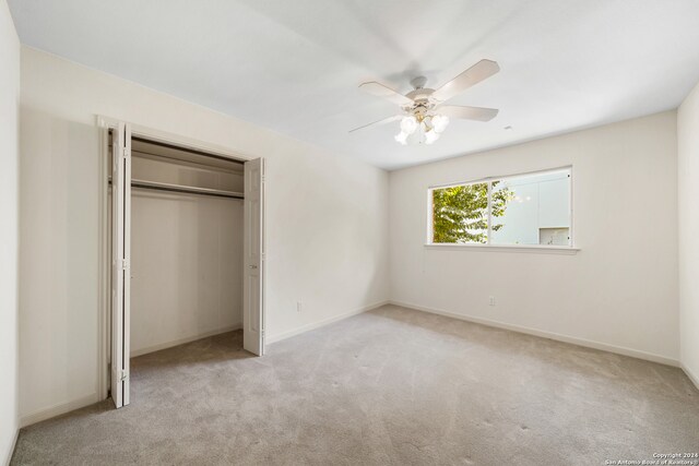 unfurnished bedroom with ceiling fan, a closet, and light colored carpet