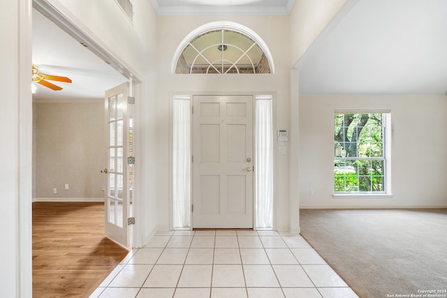 carpeted entrance foyer featuring crown molding and ceiling fan