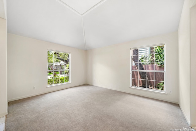 carpeted empty room featuring lofted ceiling