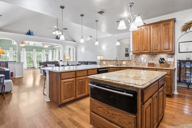 kitchen featuring ceiling fan, a center island, light wood-type flooring, tasteful backsplash, and sink