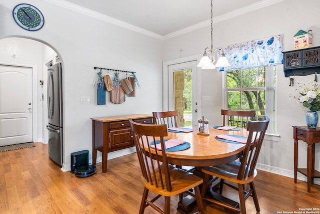 dining space with a notable chandelier, crown molding, and hardwood / wood-style flooring