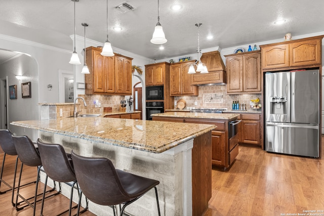 kitchen featuring decorative backsplash, light wood-type flooring, premium range hood, and black appliances