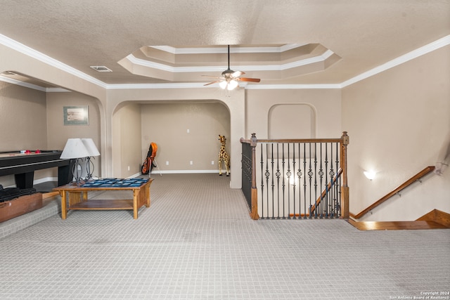 interior space featuring ceiling fan, a raised ceiling, ornamental molding, and carpet