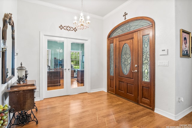 entryway featuring french doors, a chandelier, ornamental molding, and light hardwood / wood-style floors