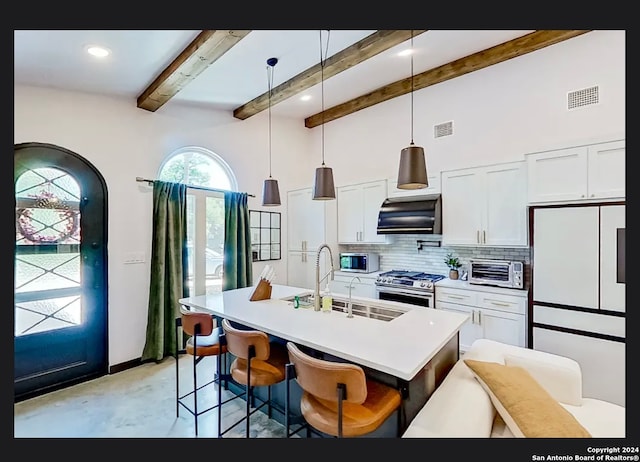 kitchen featuring ventilation hood, decorative light fixtures, stainless steel appliances, a kitchen breakfast bar, and a center island with sink