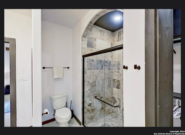 bathroom featuring toilet, a shower with shower door, and tile patterned floors