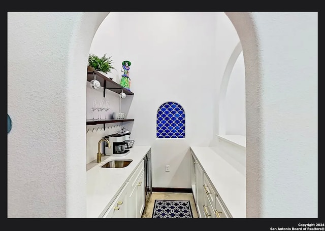 bar with white cabinets, sink, and light tile patterned flooring