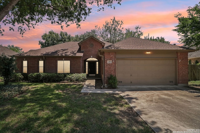 ranch-style home with a garage and a yard