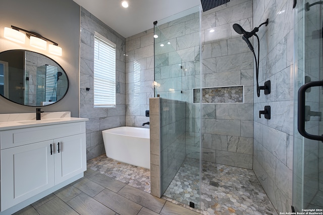 bathroom with tile patterned flooring, vanity, tile walls, and independent shower and bath