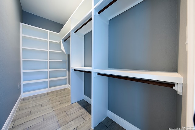 walk in closet with light hardwood / wood-style floors