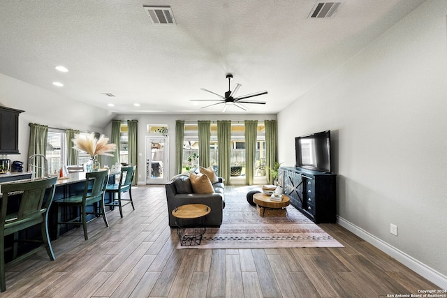 living room featuring ceiling fan, french doors, wood-type flooring, and a textured ceiling