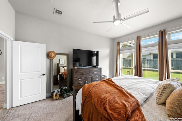 bedroom with light colored carpet, ceiling fan, and multiple windows