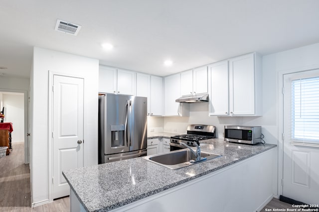 kitchen featuring stainless steel appliances, light wood-type flooring, white cabinetry, light stone counters, and kitchen peninsula