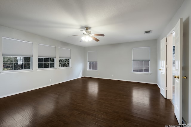 spare room with dark wood-type flooring, ceiling fan, and a healthy amount of sunlight