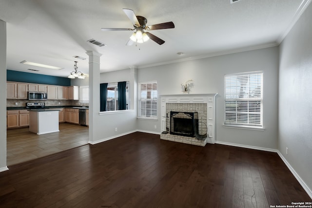 unfurnished living room with crown molding, a fireplace, ceiling fan with notable chandelier, and tile patterned flooring