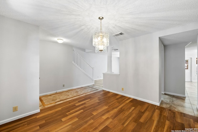 interior space featuring baseboards, visible vents, stairway, wood finished floors, and a textured ceiling