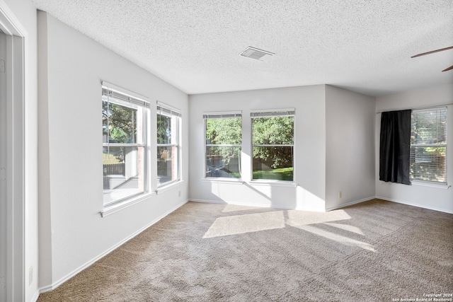 unfurnished room featuring carpet, visible vents, a textured ceiling, and baseboards