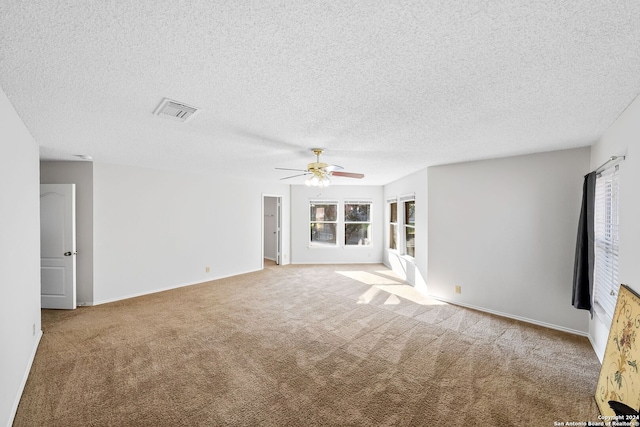 spare room featuring baseboards, visible vents, light colored carpet, ceiling fan, and a textured ceiling