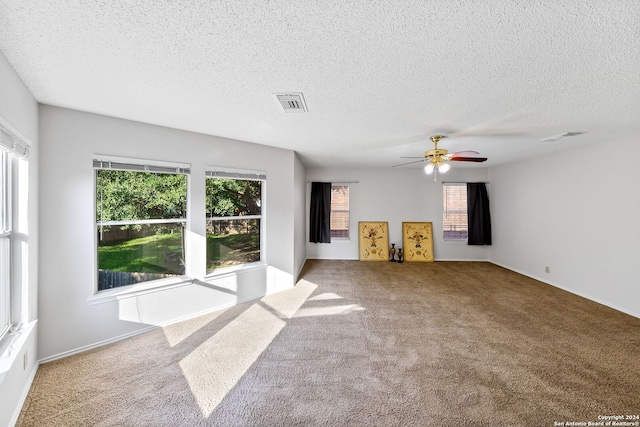 unfurnished living room with a textured ceiling, carpet flooring, and visible vents