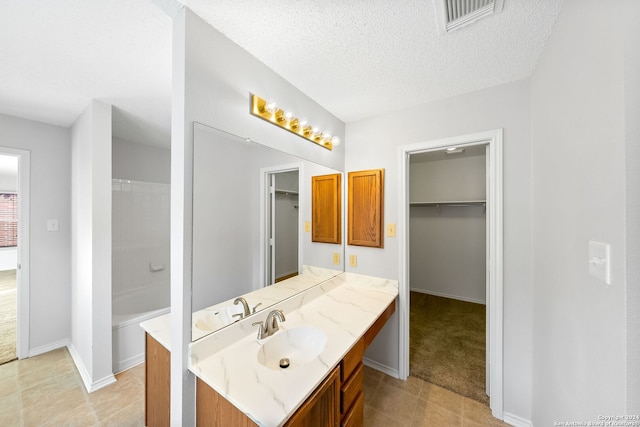 full bath with a textured ceiling, tile patterned flooring, visible vents, vanity, and baseboards