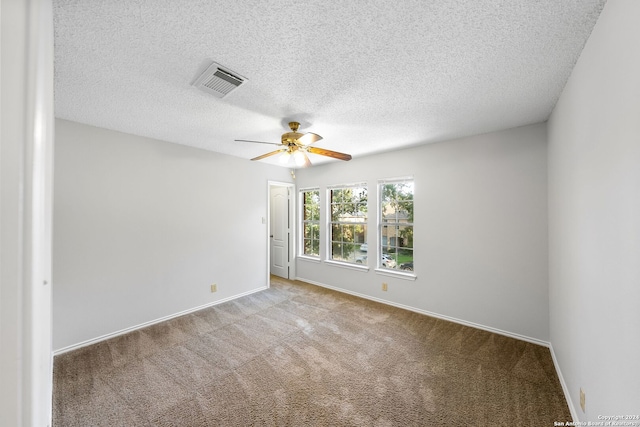 carpeted spare room featuring a ceiling fan, visible vents, a textured ceiling, and baseboards