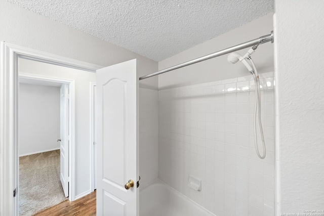 bathroom with bathing tub / shower combination, a textured ceiling, and wood finished floors